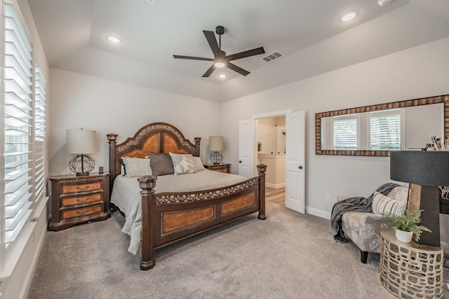 carpeted bedroom with a tray ceiling, ensuite bath, and ceiling fan