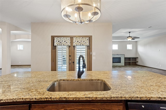 kitchen featuring light stone counters, sink, ceiling fan with notable chandelier, and french doors