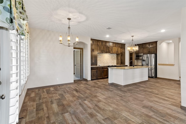 kitchen featuring sink, appliances with stainless steel finishes, a notable chandelier, pendant lighting, and a kitchen island with sink