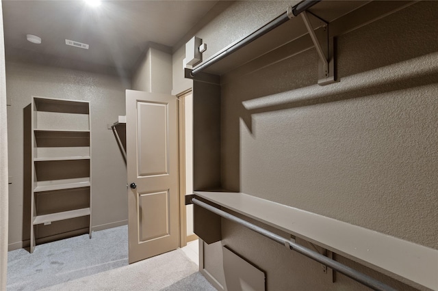 walk in closet with light carpet