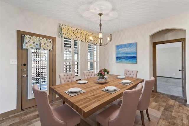 dining area with dark wood-type flooring and a notable chandelier