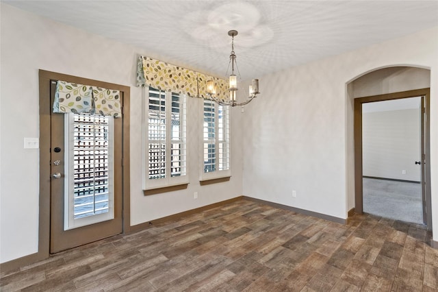 unfurnished dining area with dark hardwood / wood-style floors and a notable chandelier