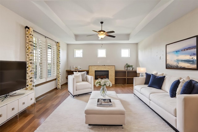 living room featuring dark hardwood / wood-style floors, a raised ceiling, and ceiling fan