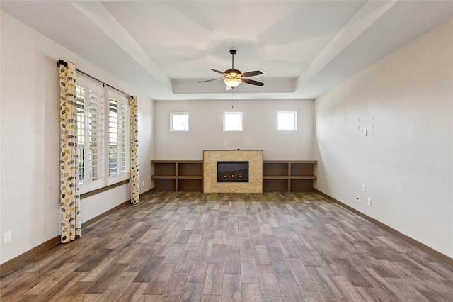 unfurnished living room with hardwood / wood-style flooring, ceiling fan, and a tray ceiling