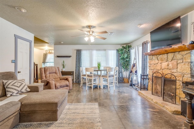 living room with a fireplace, a textured ceiling, ceiling fan, and concrete floors