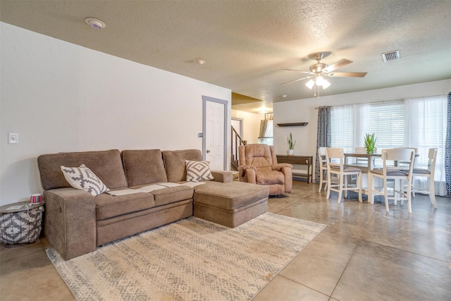 living room featuring a textured ceiling, concrete floors, and ceiling fan