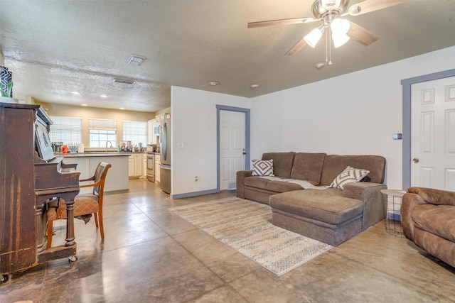 living room featuring ceiling fan, sink, and a textured ceiling