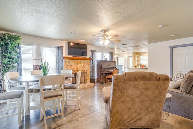 dining area with ceiling fan, a fireplace, and a textured ceiling