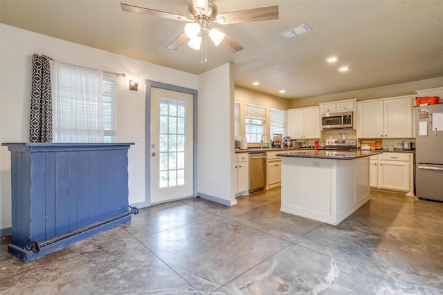 kitchen with a center island, sink, ceiling fan, appliances with stainless steel finishes, and white cabinetry