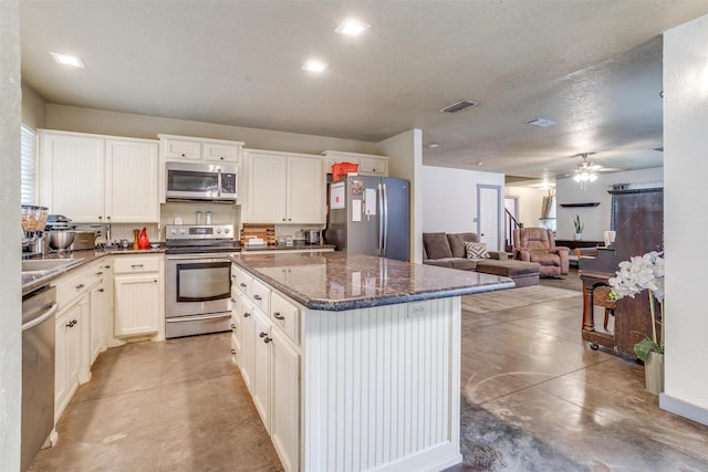 kitchen featuring white cabinets, a kitchen island, concrete flooring, and stainless steel appliances