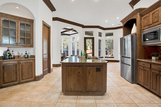 kitchen featuring appliances with stainless steel finishes, a kitchen island with sink, crown molding, sink, and light tile patterned flooring