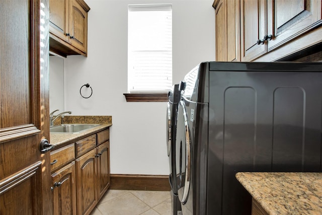 laundry area featuring cabinets, light tile patterned floors, sink, and a wealth of natural light