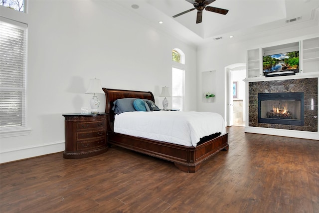 bedroom with multiple windows, ceiling fan, a high ceiling, and dark hardwood / wood-style floors