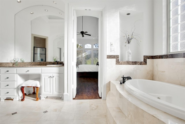 bathroom with vanity, ceiling fan, hardwood / wood-style floors, and a relaxing tiled tub