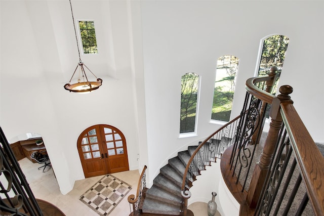 entryway featuring french doors, a towering ceiling, and plenty of natural light