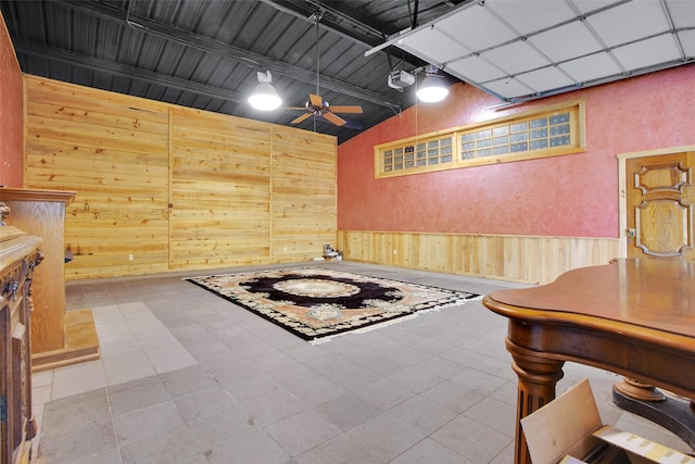 interior space featuring ceiling fan, wooden walls, and high vaulted ceiling