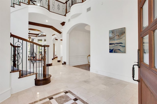 foyer with beam ceiling, crown molding, and a high ceiling