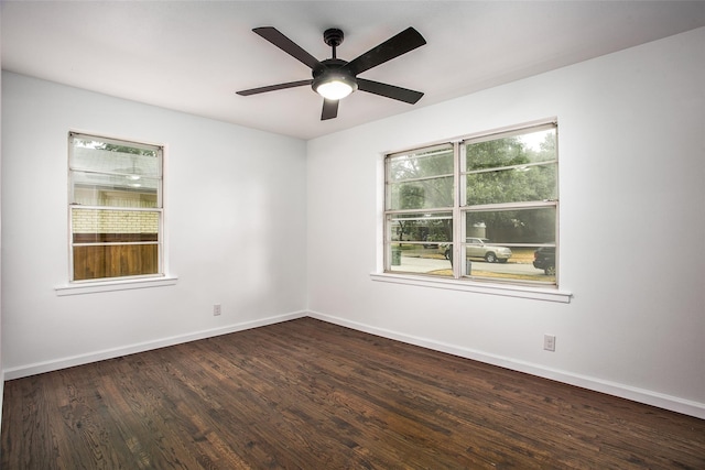 empty room featuring plenty of natural light, dark wood-type flooring, and ceiling fan