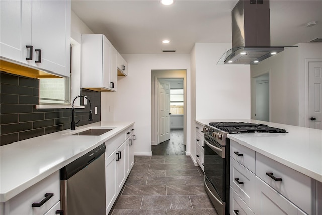 kitchen featuring sink, appliances with stainless steel finishes, white cabinets, island exhaust hood, and decorative backsplash