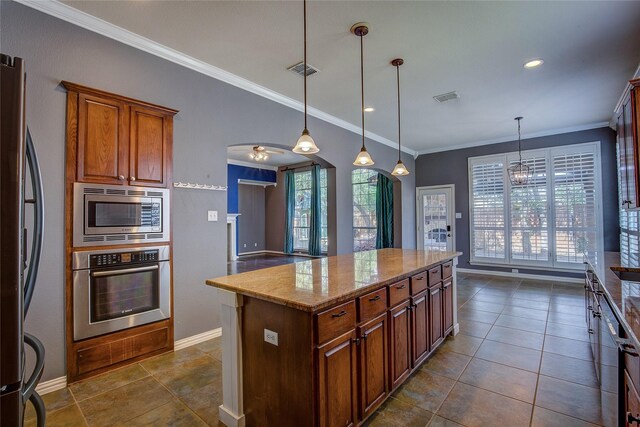 kitchen with a center island, ceiling fan with notable chandelier, ornamental molding, appliances with stainless steel finishes, and light stone counters