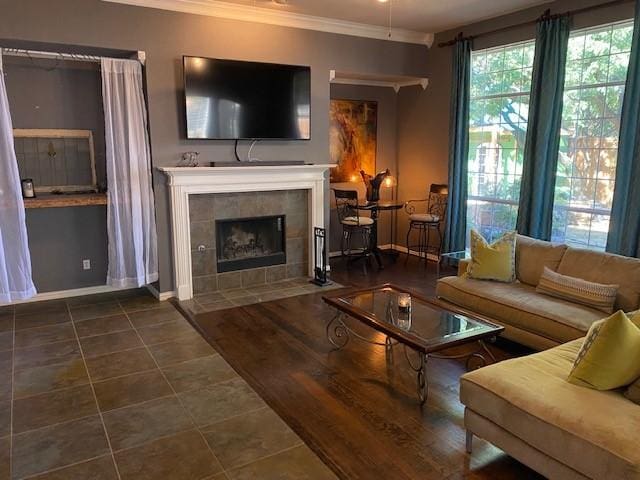 living room featuring a tile fireplace, dark tile patterned flooring, and ornamental molding