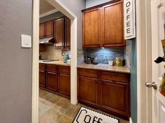 kitchen featuring backsplash, stainless steel gas stovetop, and ornamental molding