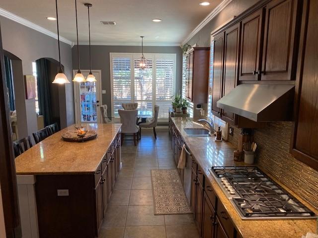 kitchen featuring decorative backsplash, stainless steel appliances, extractor fan, a center island, and hanging light fixtures