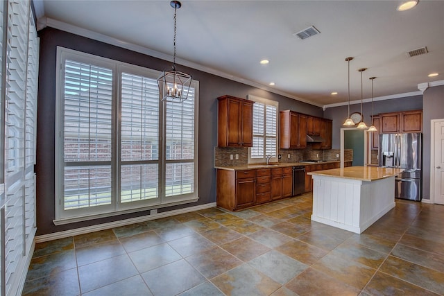 kitchen featuring backsplash, stainless steel appliances, sink, a kitchen island, and hanging light fixtures