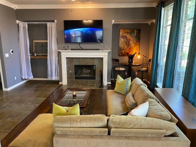 living room featuring a tile fireplace and crown molding