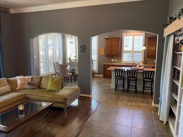 living room with crown molding, dark tile patterned floors, a healthy amount of sunlight, and sink