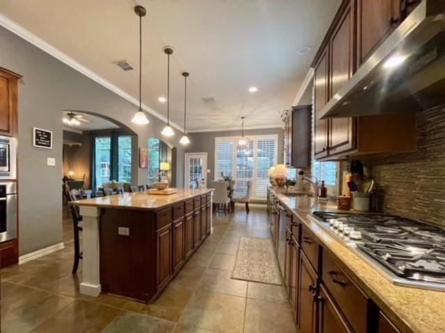 kitchen featuring a center island, pendant lighting, a kitchen bar, appliances with stainless steel finishes, and ornamental molding