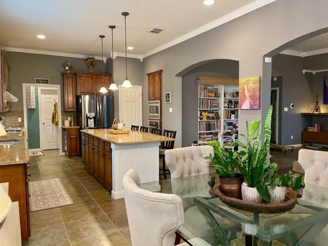 kitchen featuring appliances with stainless steel finishes, tasteful backsplash, ornamental molding, and pendant lighting