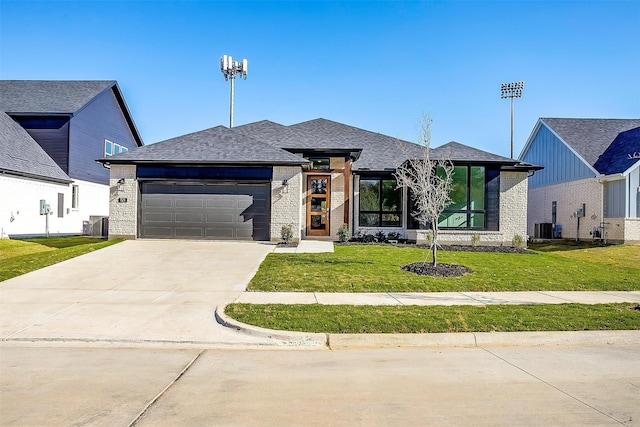 view of front facade with a garage, a front lawn, and central air condition unit