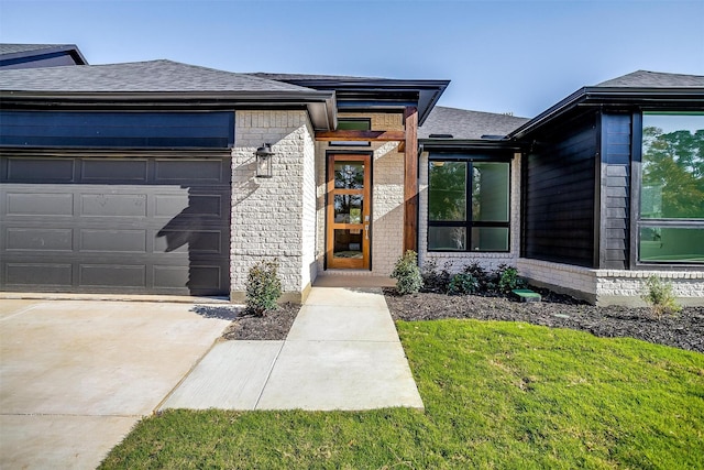 doorway to property with a garage and a lawn