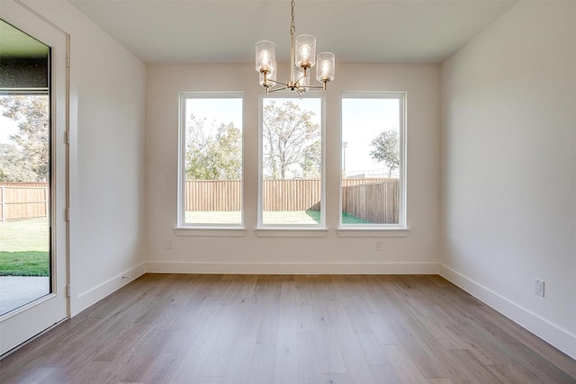 unfurnished dining area featuring a chandelier and light wood-type flooring