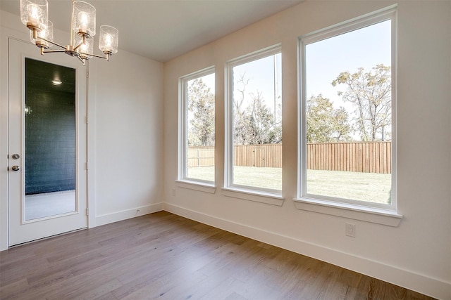 unfurnished dining area with hardwood / wood-style flooring and a notable chandelier