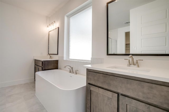 bathroom with a washtub, vanity, and tile patterned flooring