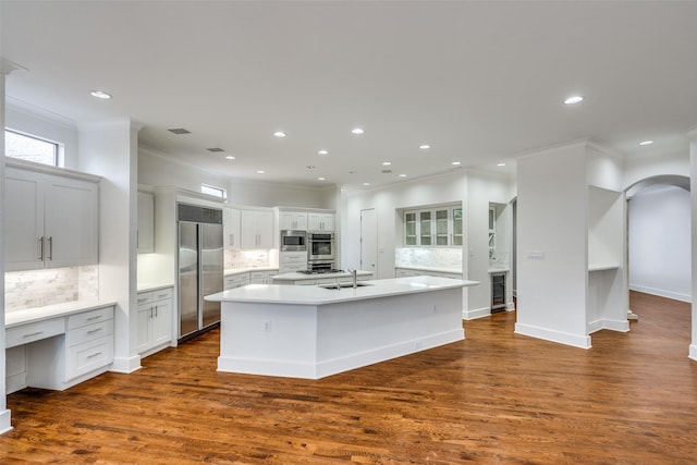 kitchen with white cabinetry, beverage cooler, dark hardwood / wood-style flooring, built in appliances, and a center island with sink