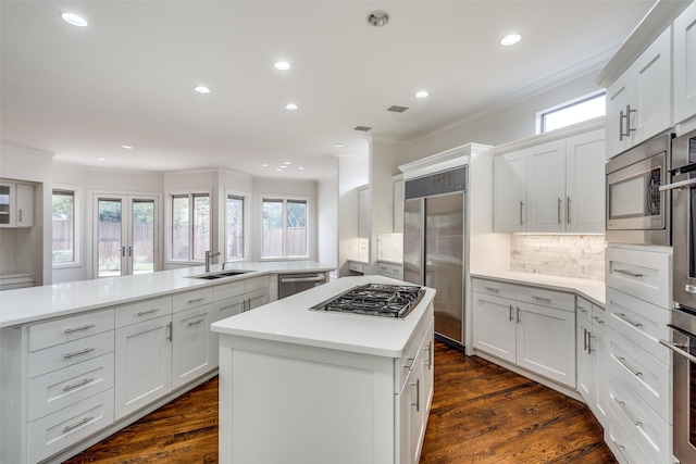 kitchen with built in appliances, white cabinetry, kitchen peninsula, and a kitchen island