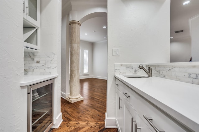 interior space with sink, white cabinets, dark hardwood / wood-style flooring, beverage cooler, and crown molding