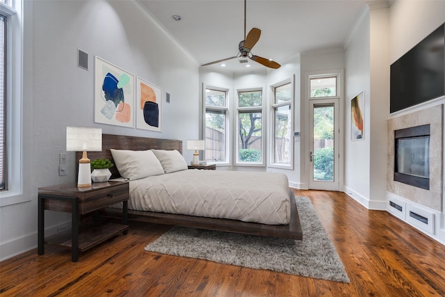 bedroom featuring dark wood-type flooring, ceiling fan, a fireplace, ornamental molding, and access to outside