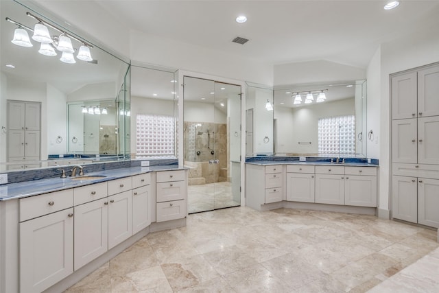 bathroom with tiled shower, vanity, and vaulted ceiling