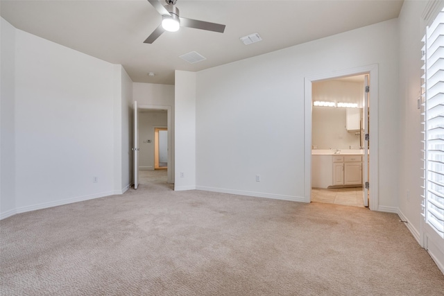 unfurnished bedroom featuring connected bathroom, light colored carpet, and ceiling fan