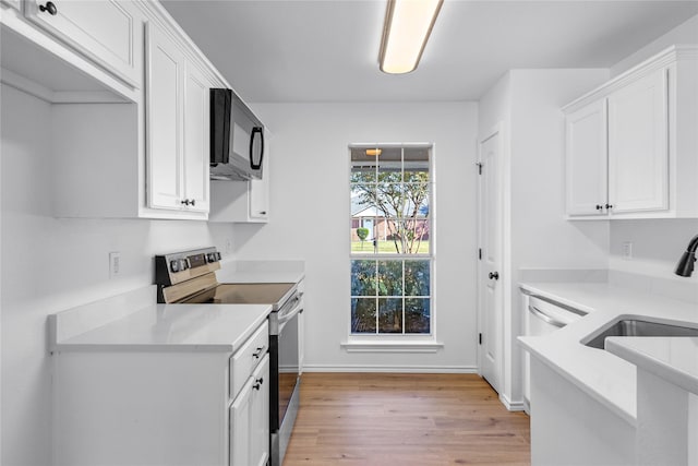 kitchen with white cabinets, sink, light wood-type flooring, and stainless steel range with electric cooktop