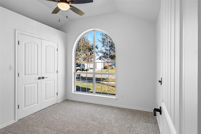 empty room featuring lofted ceiling, carpet floors, a wealth of natural light, and ceiling fan