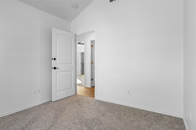 carpeted spare room with vaulted ceiling