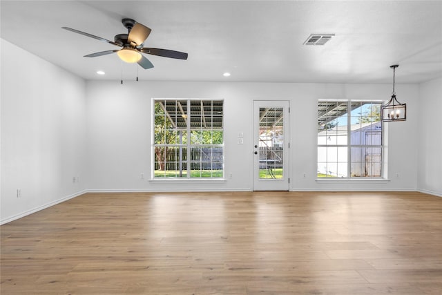 spare room featuring ceiling fan with notable chandelier and light hardwood / wood-style floors