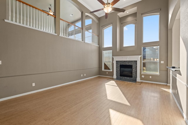 unfurnished living room featuring ceiling fan, a towering ceiling, and light hardwood / wood-style flooring