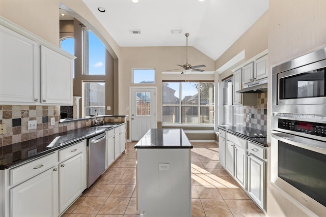 kitchen featuring white cabinets, decorative backsplash, a center island, and appliances with stainless steel finishes