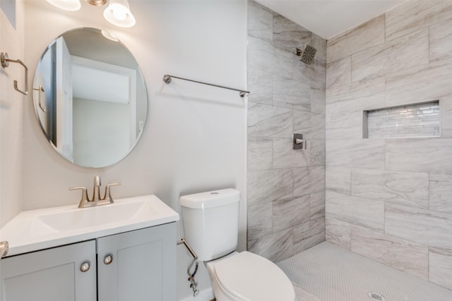 bathroom featuring vanity, a tile shower, and toilet